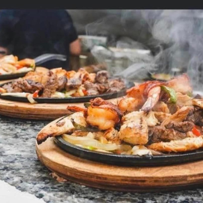 Sizzling fajitas with steak, shrimp, and vegetables on a hot skillet at Agaveros Mexican Bar and Grill.